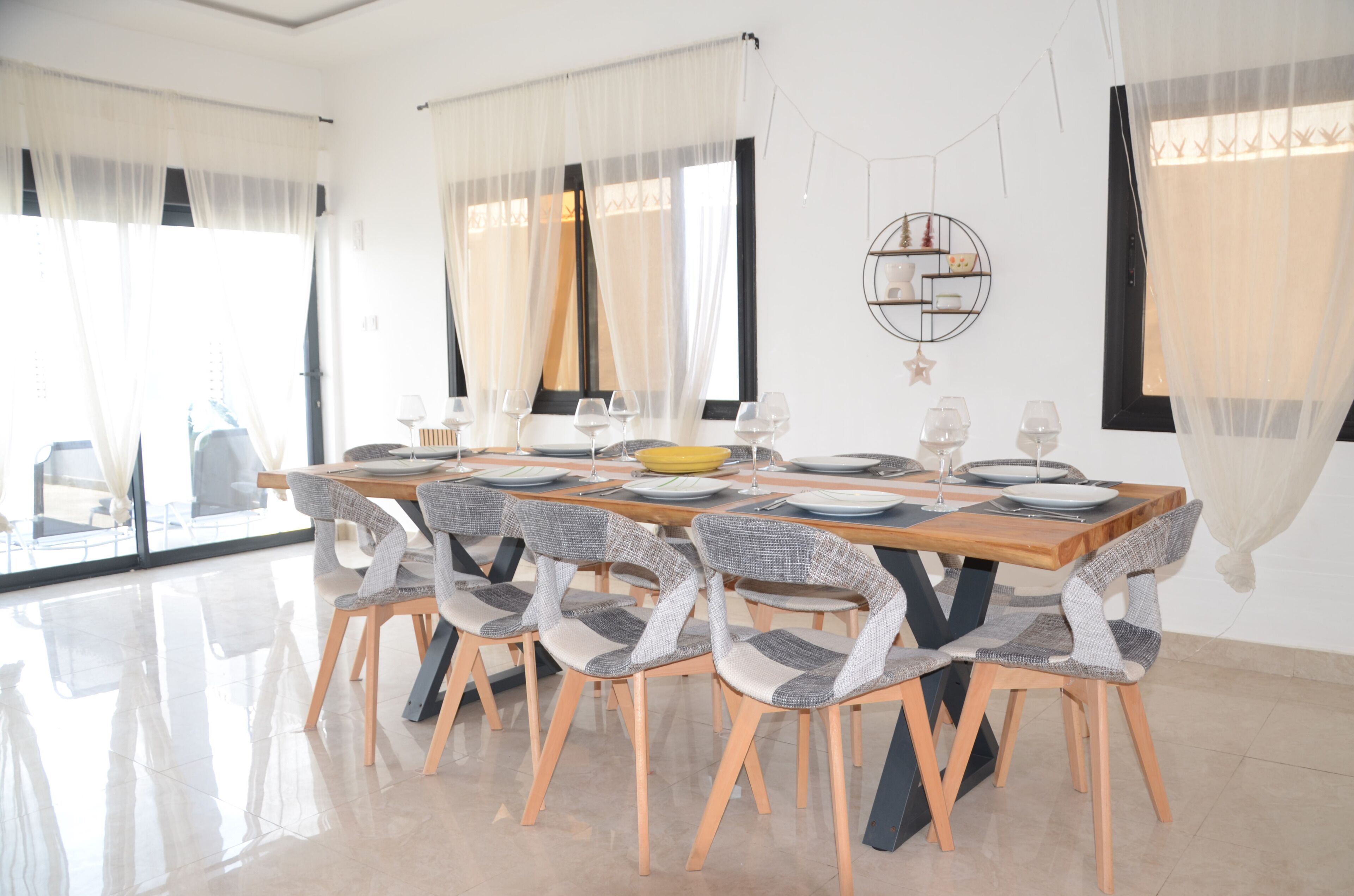 A dining area with a wooden table set for six, surrounded by six chairs with grey and white patterned upholstery.