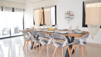 A dining area with a wooden table set for six, surrounded by six chairs with grey and white patterned upholstery.
