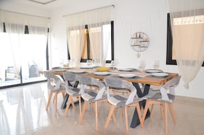 A dining area with a wooden table set for six, surrounded by six chairs with grey and white patterned upholstery.
