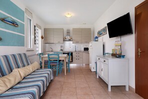 A compact living space with a kitchenette, a dining area, and a television mounted on the wall. - Apartment 'Mazzanta 308' (Mazzanta)