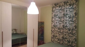 A bedroom with a bed, a wardrobe, a hanging light fixture, and a floral-patterned wall. - Apartment 'Mazzanta 308' (Mazzanta)