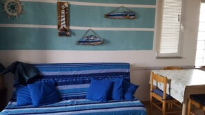 A room with a bed, a table, and wall decorations including a ship's wheel and a lighthouse. - Apartment 'Mazzanta 308' (Mazzanta)