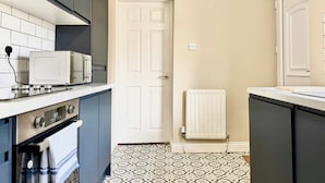 A kitchen with a microwave, oven, and a white door. - South Shields Coastal House Near Beaches- South (South Shields)