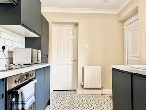 A kitchen with a microwave, oven, and a white door.