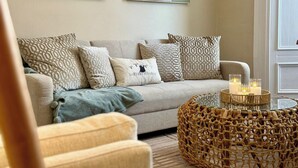 A living room with a sofa, patterned cushions, a woven coffee table, and abstract wall art. - South Shields Coastal House Near Beaches- South (South Shields)