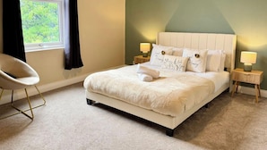 A neatly arranged bedroom with a bed, two bedside tables with lamps, a chair, and a window with curtains. - South Shields Coastal House Near Beaches- South (South Shields)