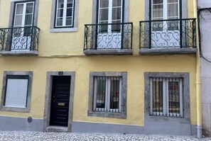 Um edifício com várias janelas, porta e varandas com grades de metal.