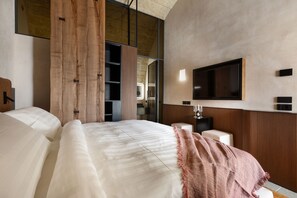 Una camera d'albergo moderna con un letto grande, una TV a parete e un pannello decorativo in legno.