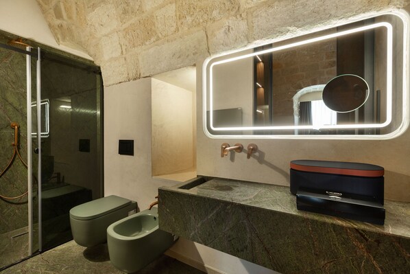 Een moderne badkamer met een douchecabine van glas, een marmeren wastafel en een grote spiegel met verlichte randen.