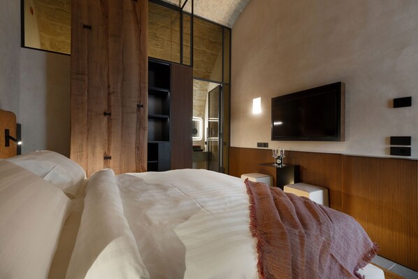 Una habitación de hotel moderna con una cama grande, un televisor de pantalla plana en la pared y un armario de madera.