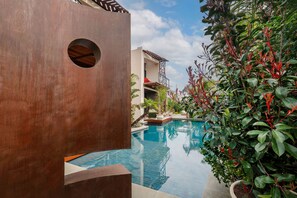 A pool area with a modern building, a circular window, and lush greenery. - Mohala Boutique Hotel - Tobacco Superior Room (Diso Spongano)