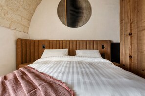 Una camera da letto con una testiera in legno, una decorazione a parete rotonda e un letto con biancheria a righe.