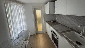 A modern kitchen with white cabinets, a marble countertop, and a built-in oven. - FRISELLA (Bari)