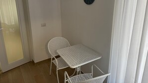 A small room with a white table and chairs, a clock on the wall, and a door with a frosted glass panel. - FRISELLA (Bari)