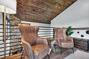 Un intérieur moderne avec deux fauteuils en cuir, un plafond en bois et un mur en pierre.