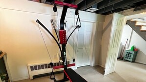 Un gimnasio en casa con una prensa de banca, una estructura para sentadillas y una barra para dominadas.