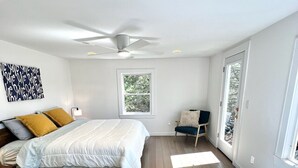 Un dormitorio con cama, ventilador de techo, ventana y bañera.