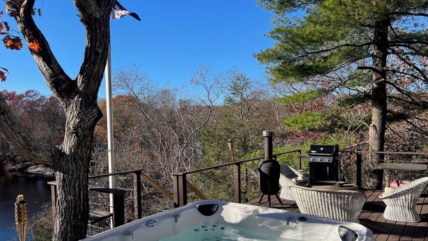 Un jacuzzi en una terraza con vistas a un lago y árboles.