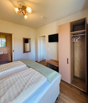 A bedroom with a bed, a wardrobe, a mirror, and a ceiling light fixture. - Enjoy your vacation at Haus Golker in Seeboden on Lake Millstatt (Seeboden/Millstätter See)
