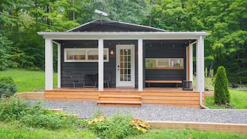A small, single-story cabin with a porch, a door, and two windows.