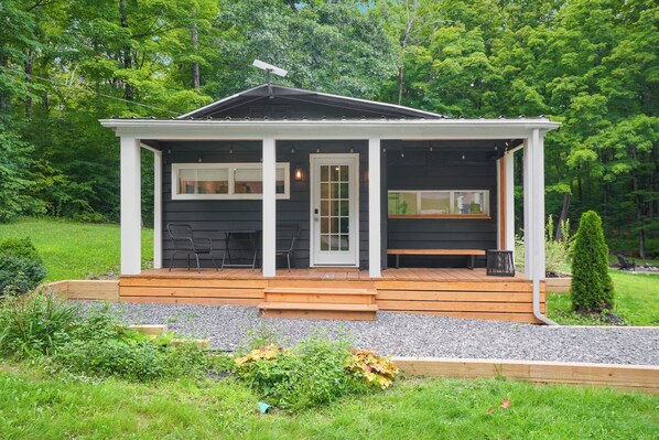A small, single-story cabin with a porch, a door, and two windows.