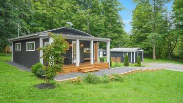 A two-story cabin with a porch, a small shed, and a well-maintained lawn.