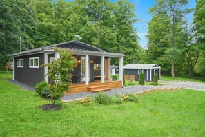 A two-story cabin with a porch, a small shed, and a well-maintained lawn.