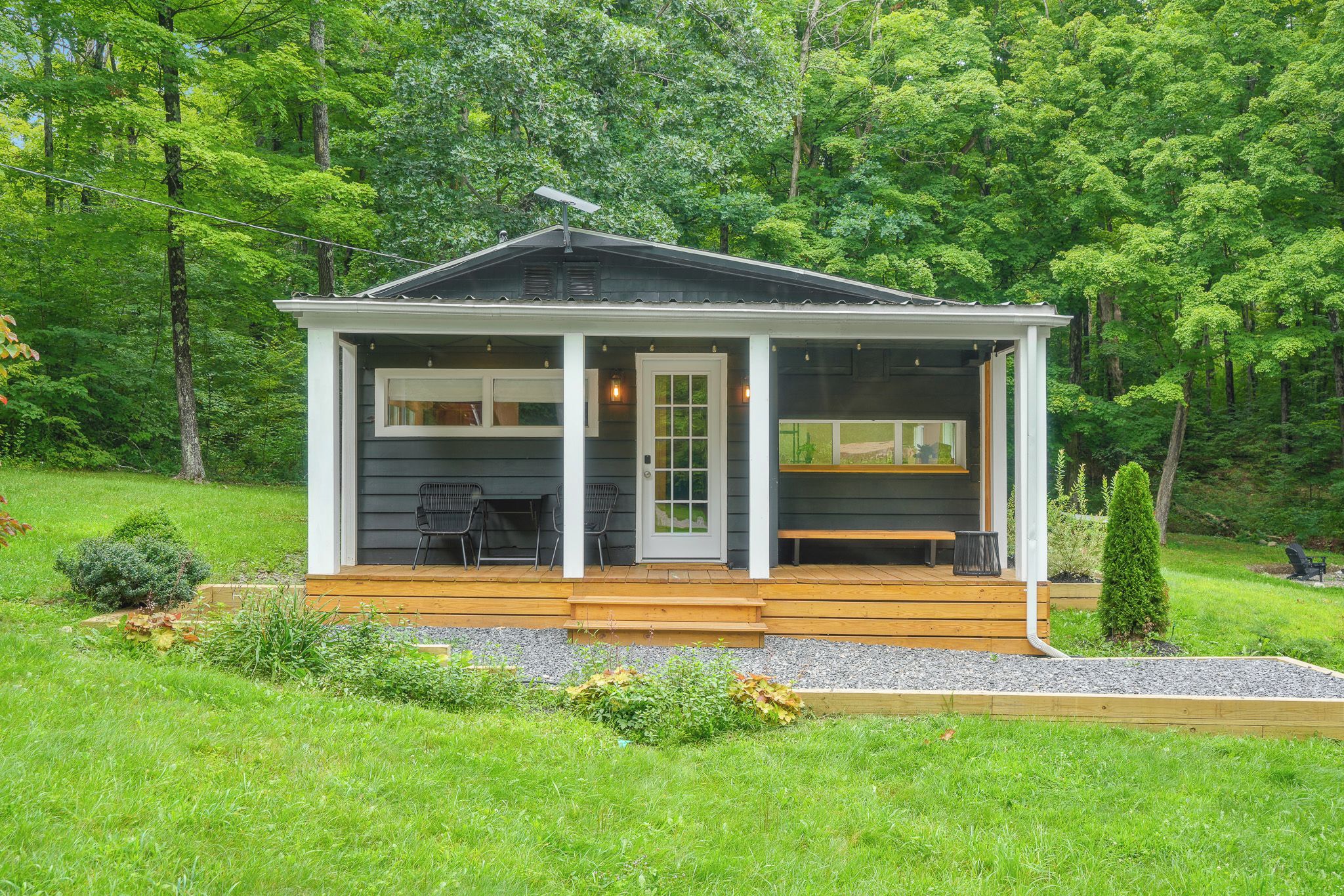 Charming forest cabin with covered porch, deck, and peaceful lawn views
