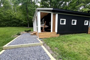 Un bâtiment moderne, de plain-pied, doté d’une terrasse en bois et d’un chemin de gravier menant à l’entrée.
