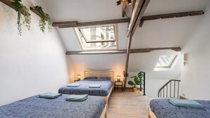 Camera da letto in stile loft con due letti, travi in legno, lucernari e una scala.