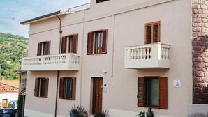 Un edificio de dos pisos con balcones, una puerta y plantas en macetas.