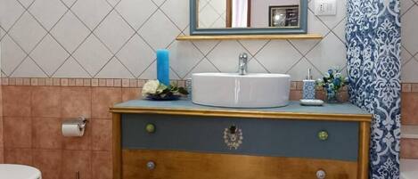 Un baño con lavamanos, espejo y elementos decorativos.