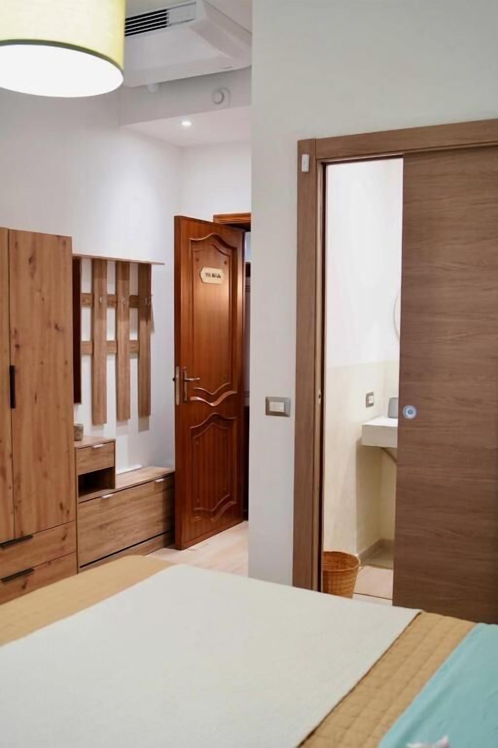 Un dormitorio con una cama, un armario de madera y una puerta que da a un baño.
