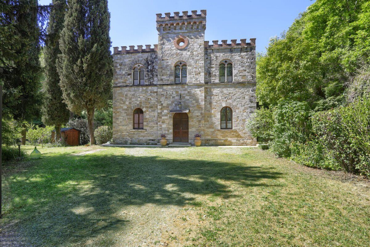 A stone building with a tower, arched windows, and a wooden door.