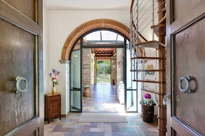 A hallway with a wooden door, a small wooden cabinet, and a potted plant. - Villa Tirassegno del Chianti (Greve in Chianti)