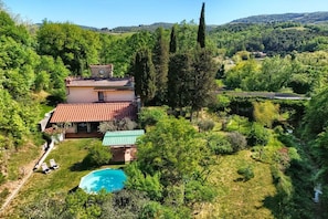A house with a swimming pool surrounded by lush greenery and hills in the background. - Villa Tirassegno del Chianti (Greve in Chianti)