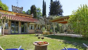 Een villa met een terras, zitplaatsen buiten en uitzicht op het omliggende landschap.