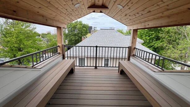 A wooden deck with a railing leading to a building's entrance. - Victoria’s Chamber Fourplex | Rooftop deck and Zoo (Omaha)