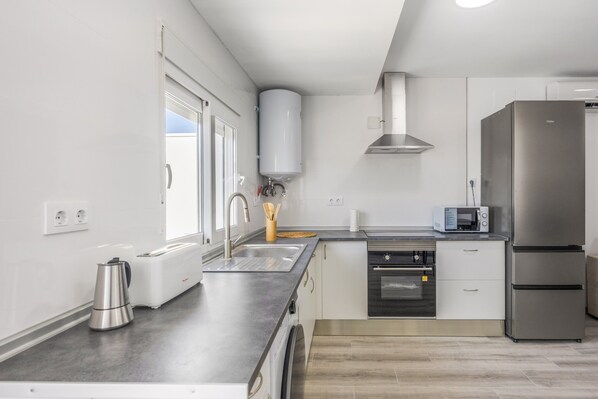 A modern kitchen with a built-in oven, microwave, and stainless steel refrigerator.