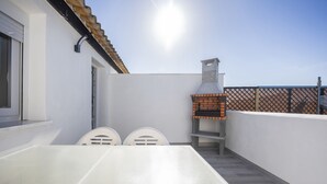 A patio with a white table and chairs, a brick oven, and a white wall. - Holiday Home 'Kaki 5' with Private Pool, Wi-Fi and Air Conditioning (Barrio Nuevo)