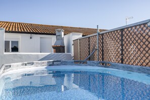 A swimming pool with a tiled roof and a chimney, surrounded by a fence and a building with a tiled roof.