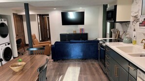 A modern kitchen with a dining area, a flat-screen TV, and a built-in oven. - The Candlelight Cellar on 10th | Fourplex (Omaha)