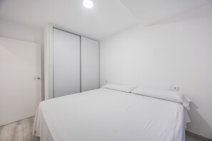 Een slaapkamer met een bed, een kledingkast en een deur.