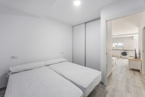 A bedroom with a bed, a wardrobe, and a view into a kitchen area. - Holiday Home 'Villa Kaki 4' with Private Pool, Wi-Fi and Air Conditioning (Barrio Nuevo)