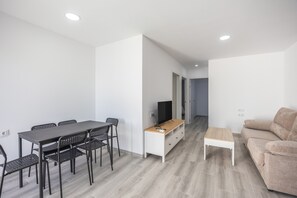A modern living room with a sofa, a coffee table, a TV on a stand, and a dining area with a table and chairs. - Holiday Home 'Villa Kaki 4' with Private Pool, Wi-Fi and Air Conditioning (Barrio Nuevo)