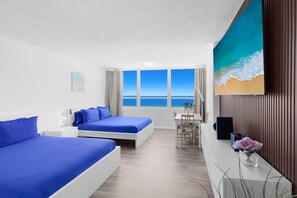 A hotel room with two beds, a desk, a chair, a TV, and a large window with a view of the sea. - 1701 - Studio Ocean Front Free Parking Pool 4 pers (Miami Beach)