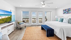 Ein Schlafzimmer mit Bett, Fernseher, Deckenventilator und Blick ins Freie.