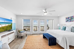 Ein Schlafzimmer mit Bett, Fernseher, Deckenventilator und Blick ins Freie.