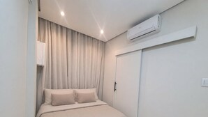 Ein Schlafzimmer mit Bett, Vorhängen, einer Klimaanlage und einem Kleiderschrank.