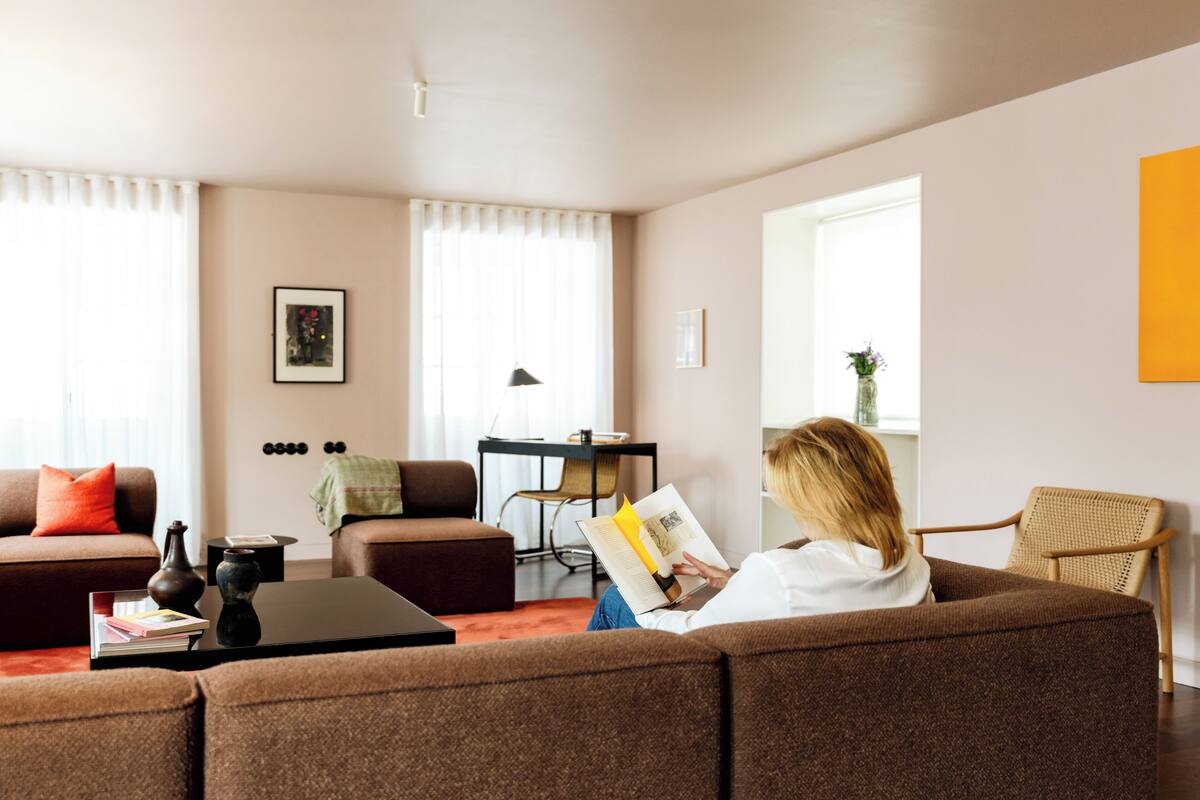 Ett vardagsrum med en soffa, ett soffbord, en bokhylla och ett fönster med gardiner.